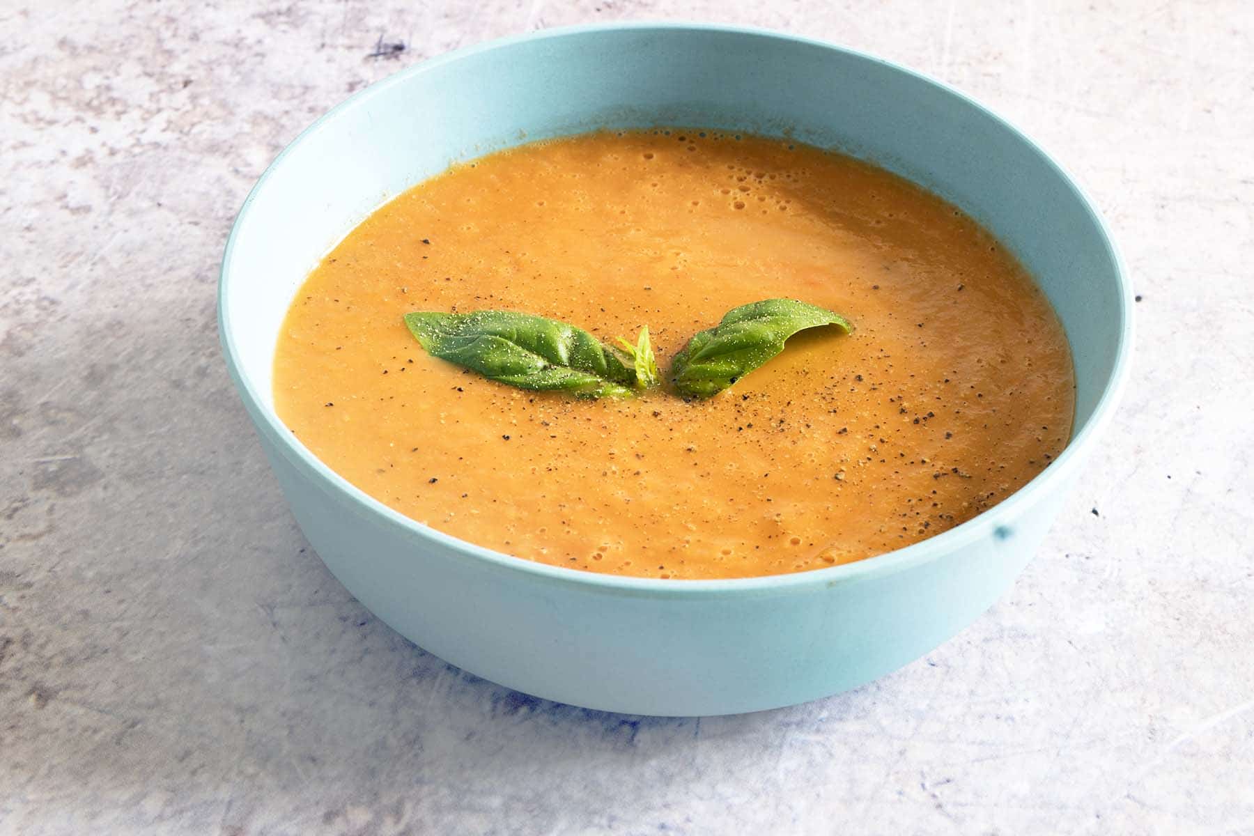 vegan tomato and basil soup in blue bowl