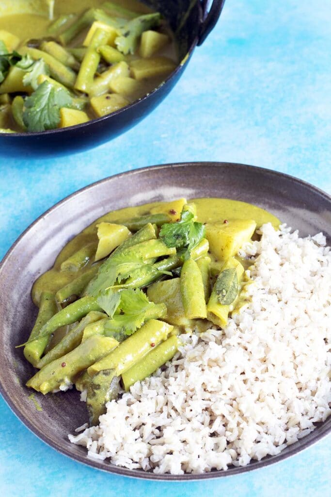 green bean curry and rice on brown ceramic plate