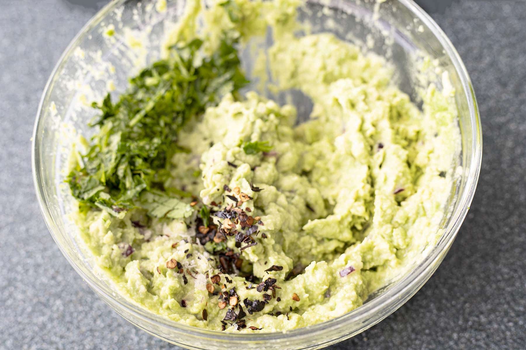 mashed avocado in bowl with chipotle and coriadner