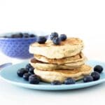 stack of peanut butter pancakes with blueberries on blue plate