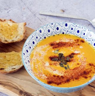 carrot soup topped with seeds in blue bowl