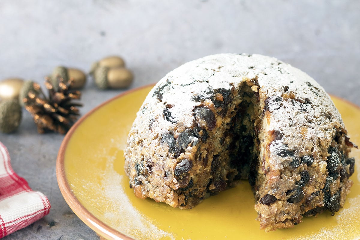 vegan christmas pudding on plate with decorations in background