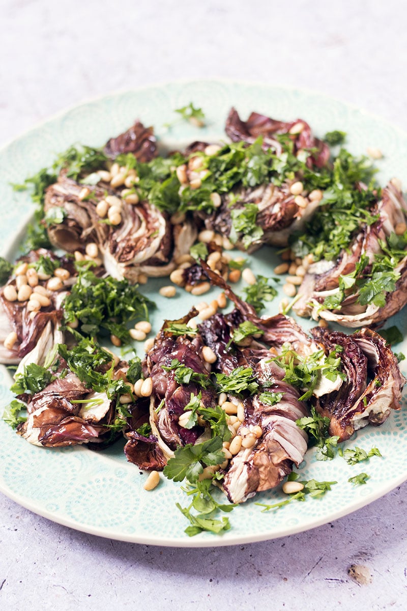roasted radicchio with pine nuts and parsley on light green platter