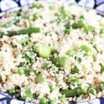 couscous salad with asparagus, broad beans and peas in blue and white bowl
