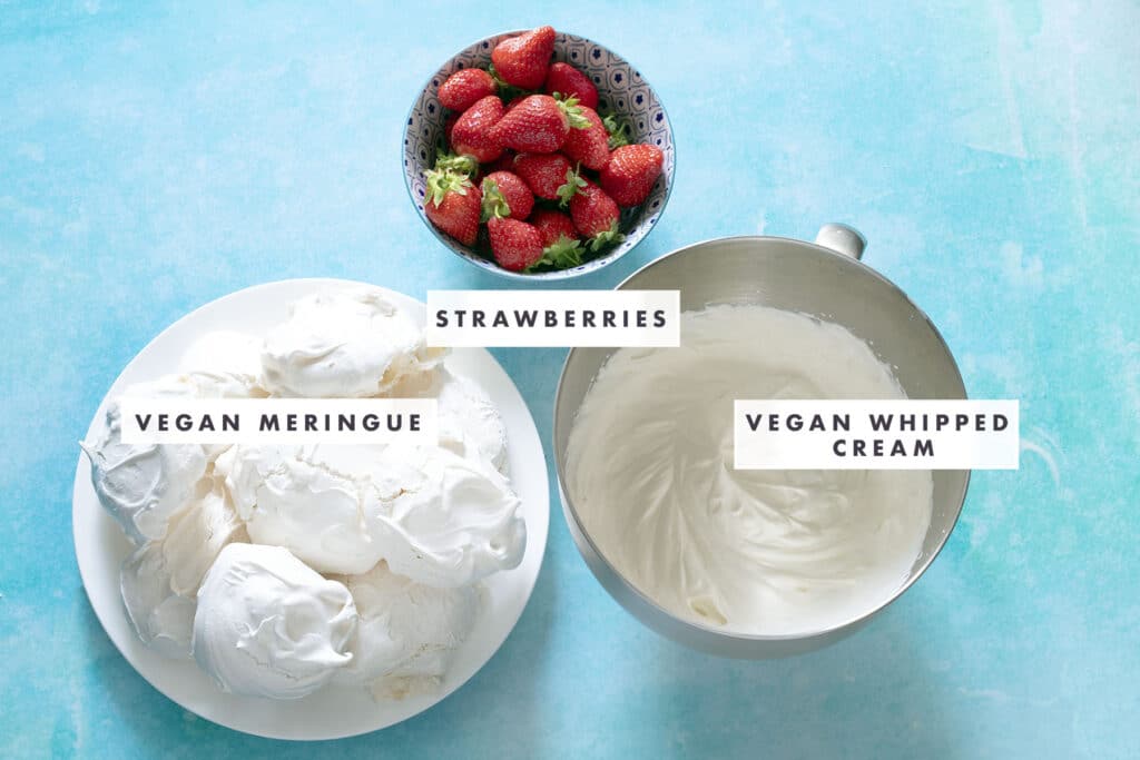 meringues, cream and strawberries on blue background