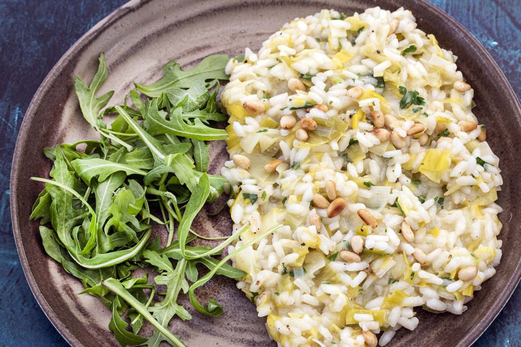 leek risotto topped with pine nuts on plate