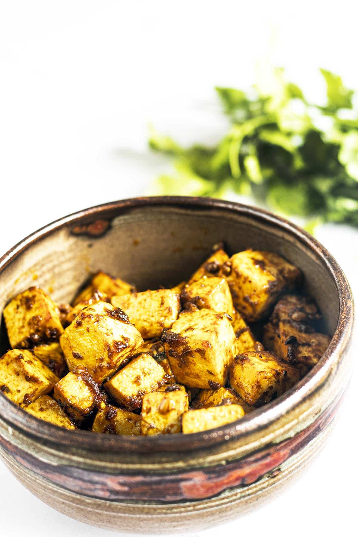 tofu tikka in ceramic bowl with coriander leaves in background