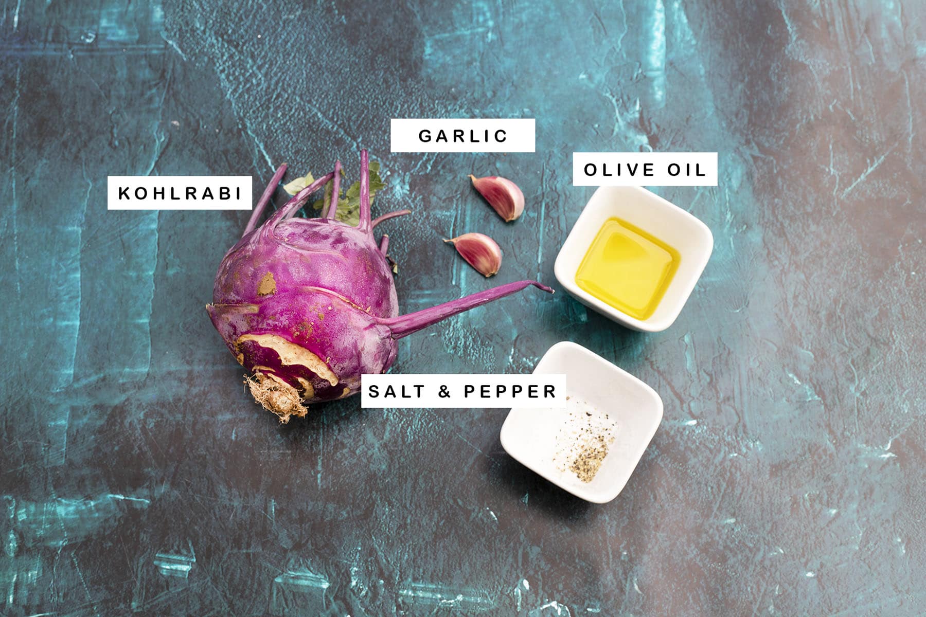 kohlrabi, garlic, olive oil, salt and pepper on blue background