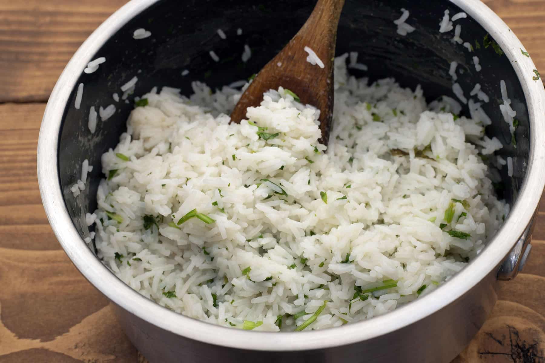 rice and herbs in pan with wooden spoon