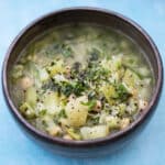broccoli stalk soup in bowl with herbs