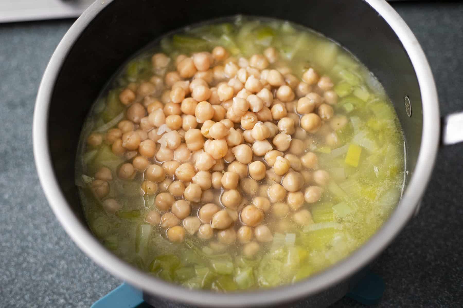 chickpeas added to broccoli stalk soup in pan